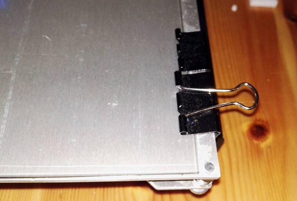 Borosilicate sheet of glass on a heatbed of 3d printer attached with binder clips